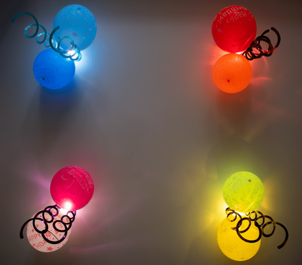 A group of four balloons with lights on them.