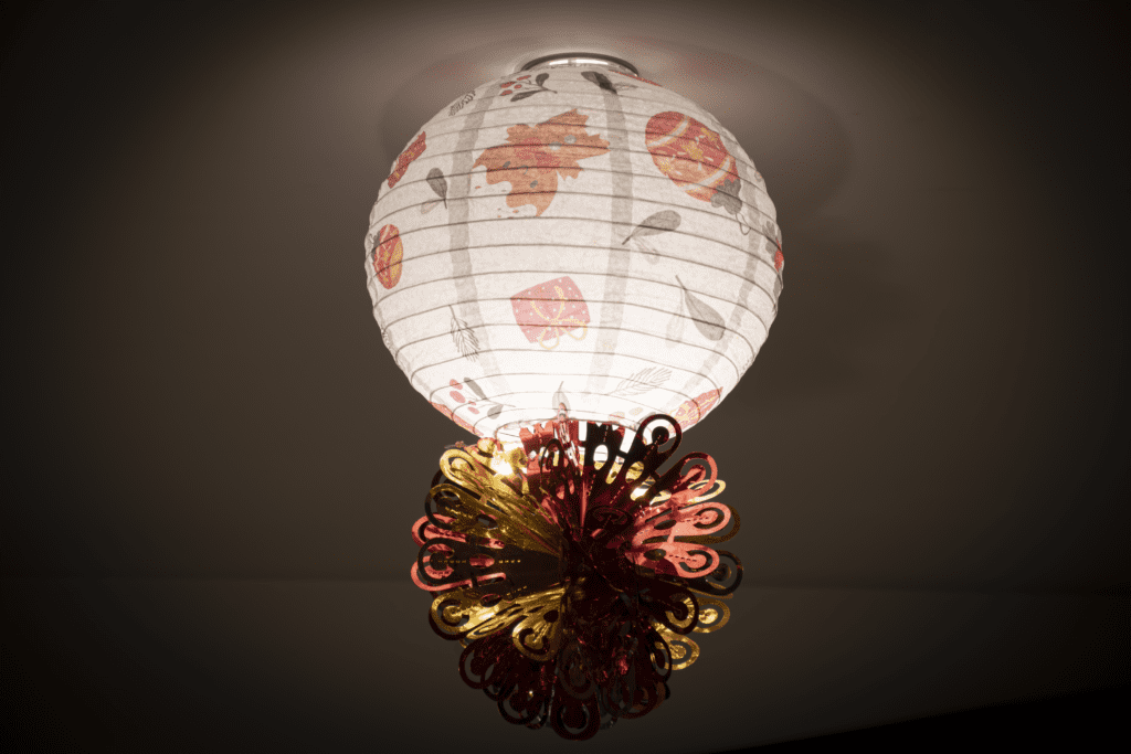 A lamp hanging from the ceiling with flowers on it.