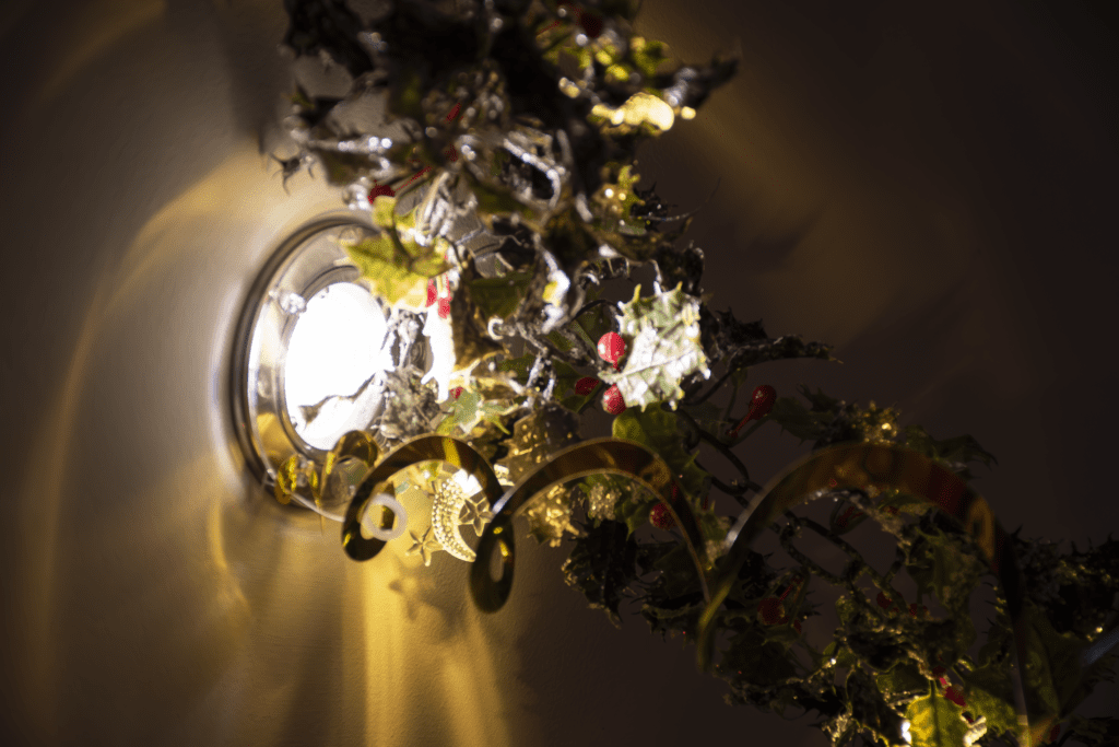 A light fixture with leaves and berries hanging from it.